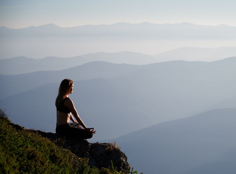 Woman meditating on mountain