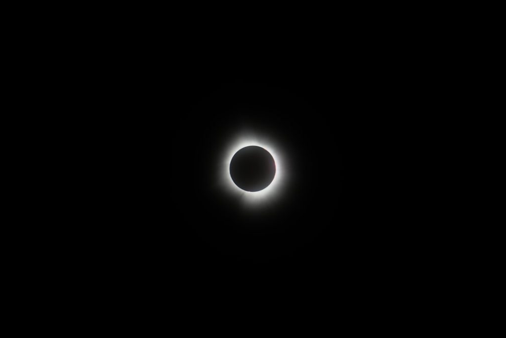 A total solar eclipse seen in a dark sky, with the sun’s corona around the moon.