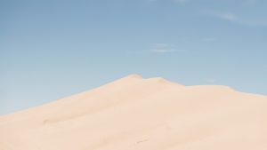 Soft desert dunes under warm light and open sky.