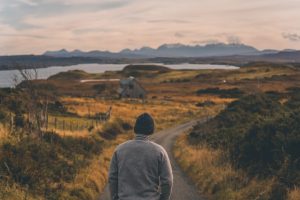 A traveller looking out across a wide landscape and water.