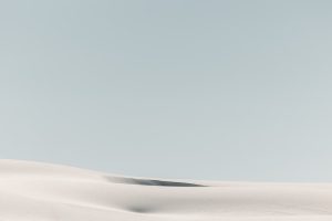 Soft pale dunes beneath a wide blue sky.