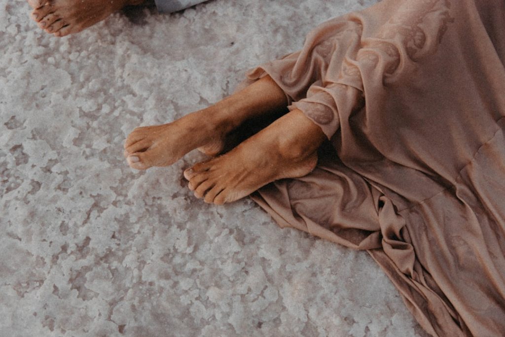 A person lying on the ground with their legs resting up, in a calm pose.