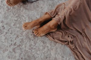A person lying on the ground with their legs resting up, in a calm pose.